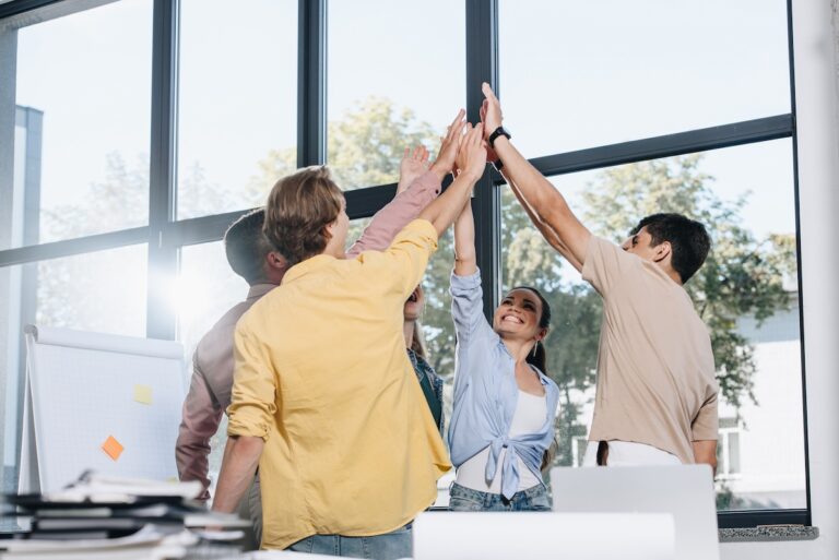 Measuring the success of Career Development Programmes image of people at work in a circle high-fiving Antoinette Oglethorpe