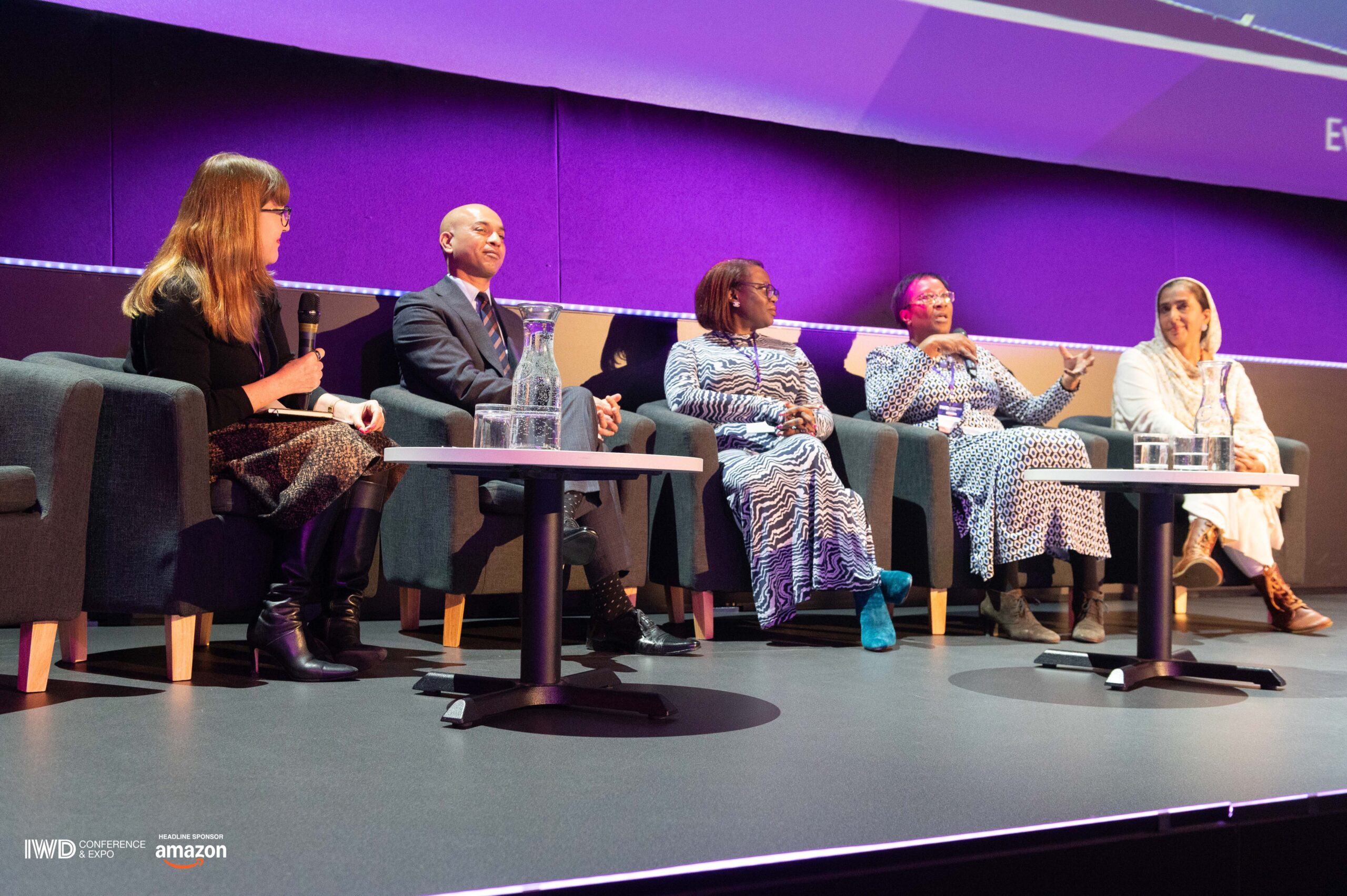 Antoinette Oglethorpe is on stage holding a mic as she hosts a panel discussion with four experts on Equity, Diversity and Inclusion at the IWD Conference & Expo 2025