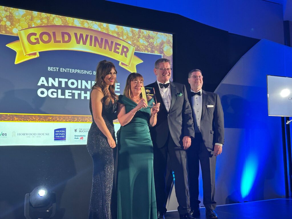 A photo of the Antionette Oglethorpe team on stage at the SME MK & Buckinghamshire Business Awards holding the Gold award for Best Enterprising Business.